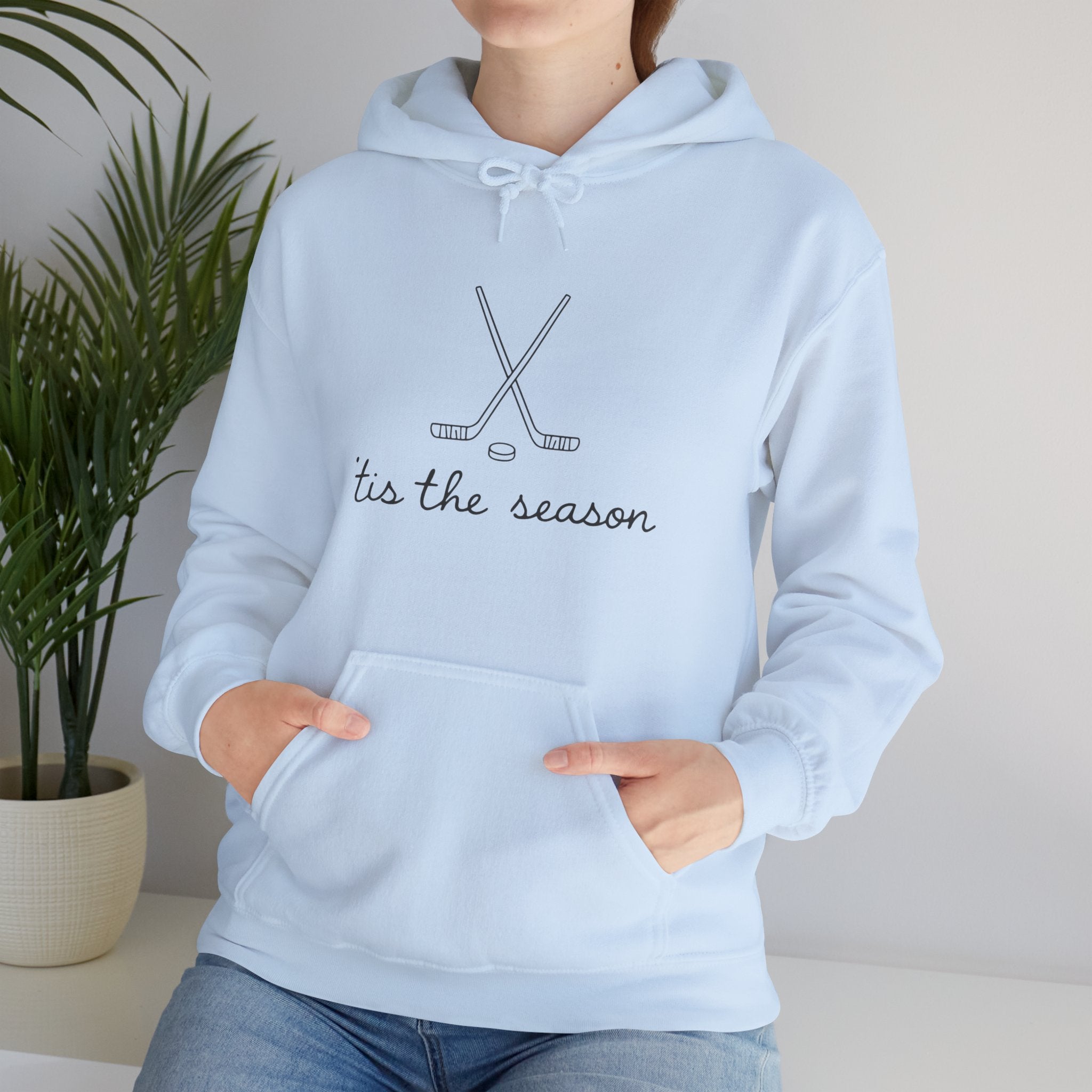 Light blue hoodie with 'tis the season and hockey stick design, worn by a person.