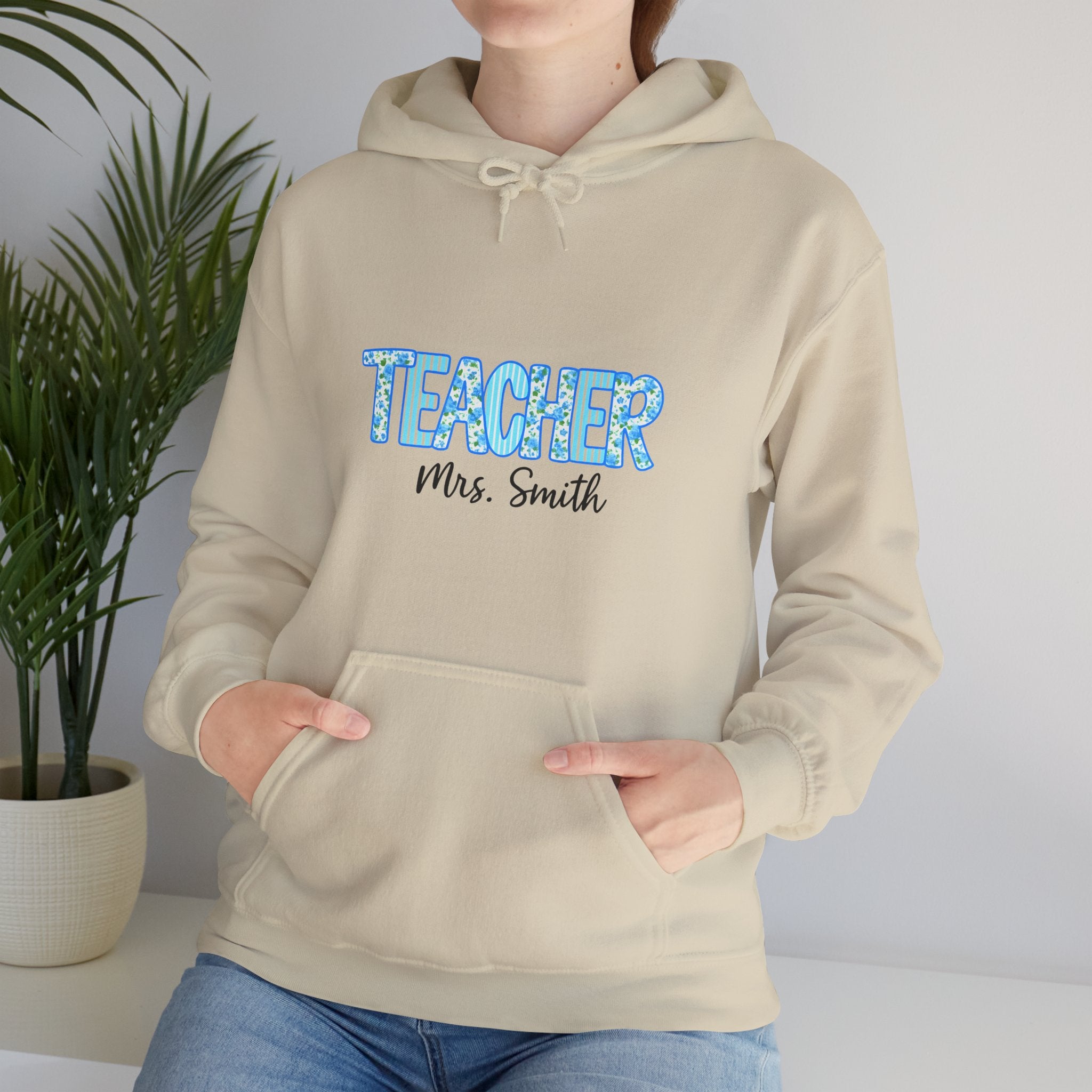 Person wearing a beige hoodie with 'TEACHER Mrs. Smith' text in blue and black.