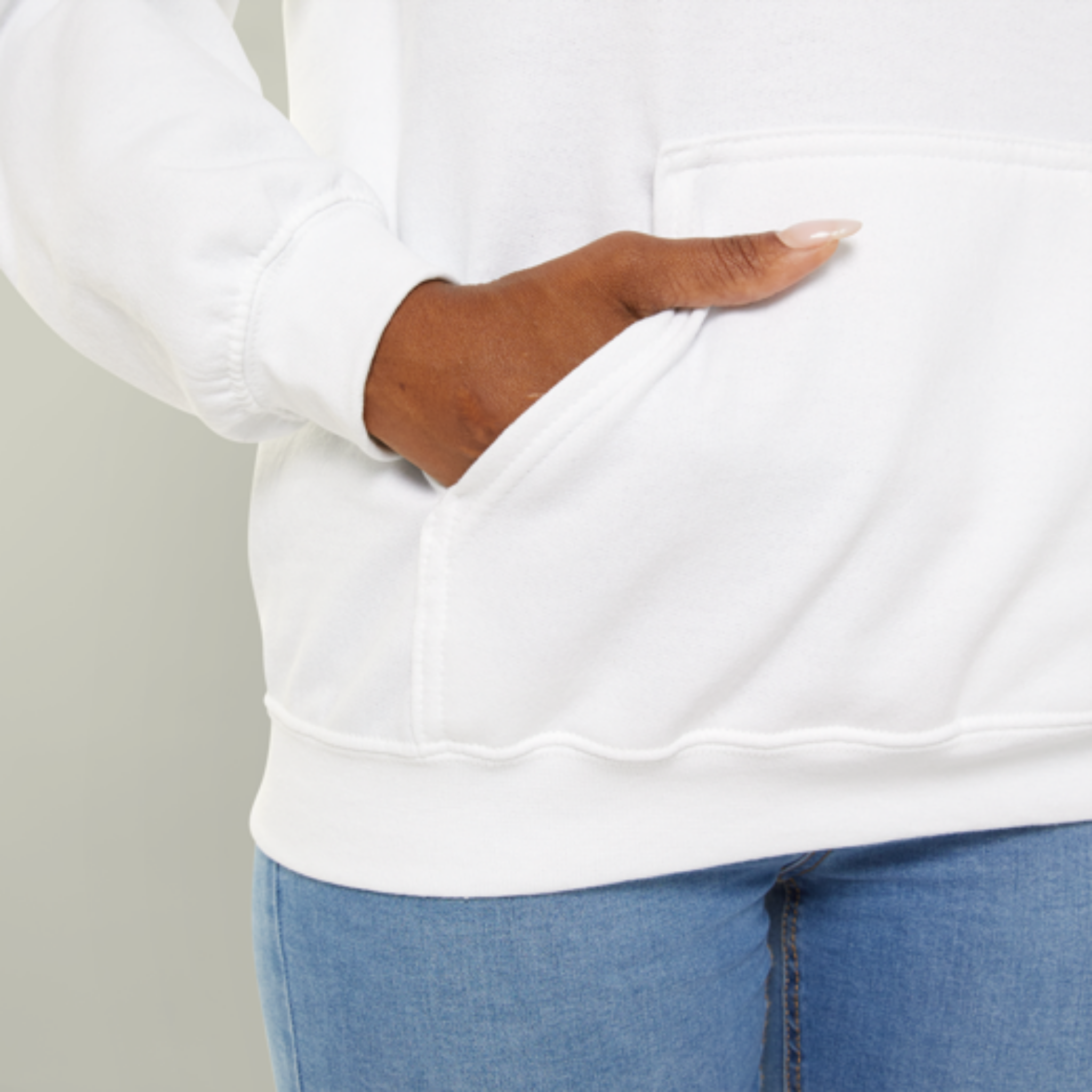 Person wearing a white sweatshirt and blue jeans with a neutral background